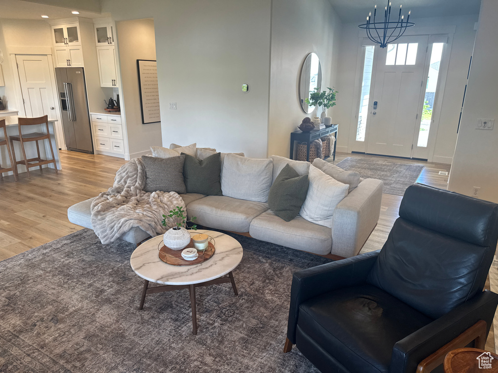 Living room featuring light wood finished floors, a chandelier, and recessed lighting