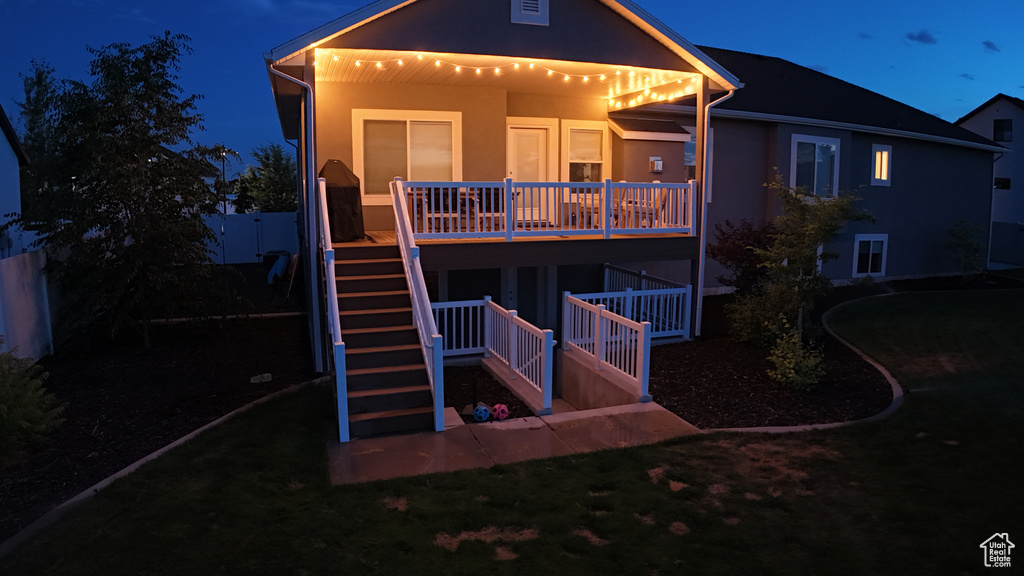 Back of property with stairway, stucco siding, and a yard