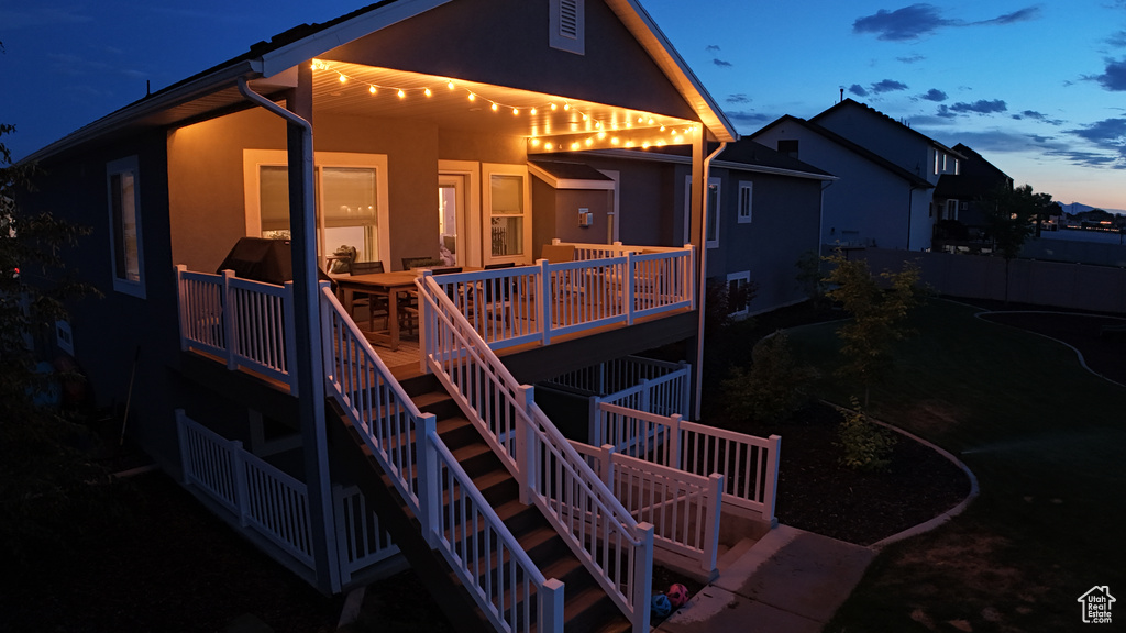 Back of house with stucco siding, stairway, and a wooden deck