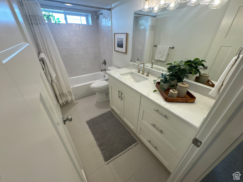 Full bath featuring vanity, shower / bath combo with shower curtain, and tile patterned floors