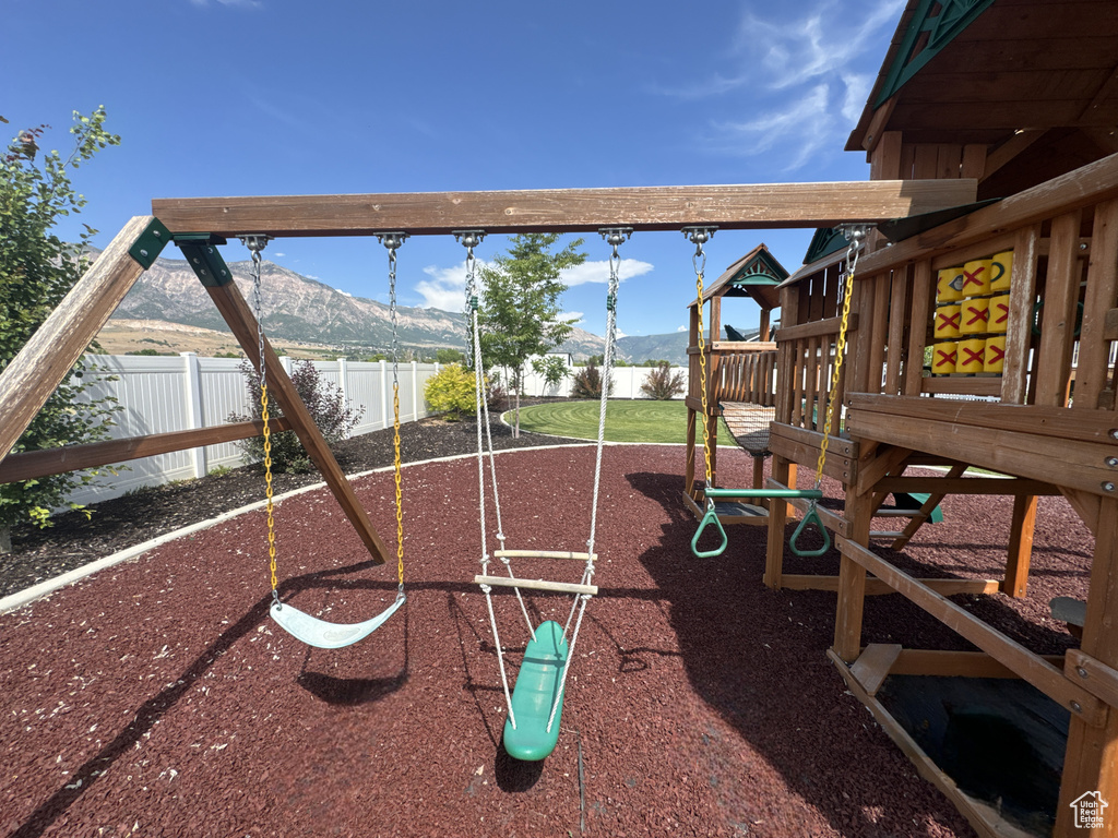 View of jungle gym featuring a mountain view and a fenced backyard