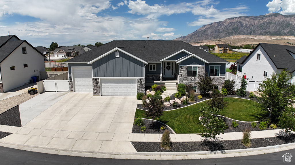 View of front of house with stone siding, an attached garage, a gate, and driveway