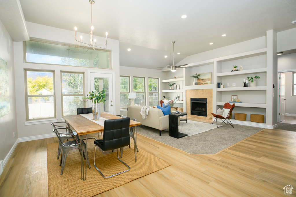 Dining space with a tile fireplace, light wood-style flooring, vaulted ceiling, built in features, and recessed lighting