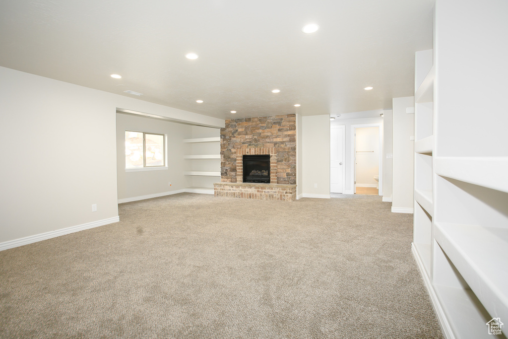 Unfurnished living room with light carpet, a fireplace, and recessed lighting