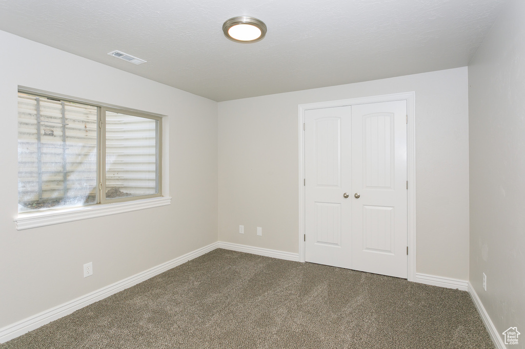 Unfurnished bedroom featuring dark carpet and a closet