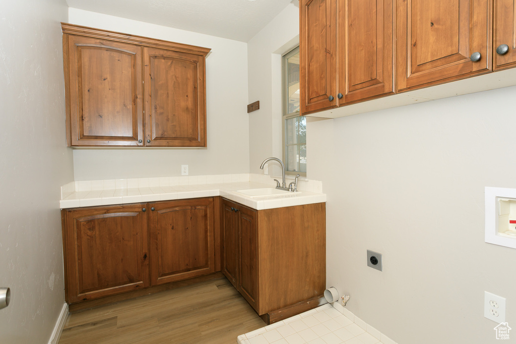 Washroom featuring hookup for an electric dryer, gas dryer hookup, cabinet space, and light wood-type flooring