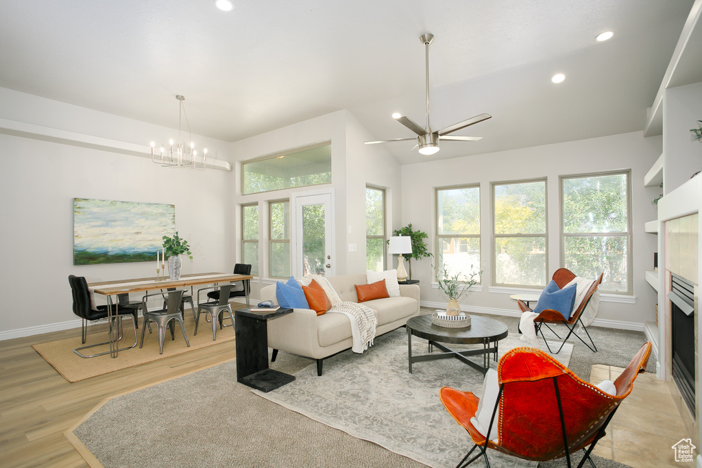Living room with recessed lighting, light wood-style flooring, a chandelier, a fireplace, and a ceiling fan
