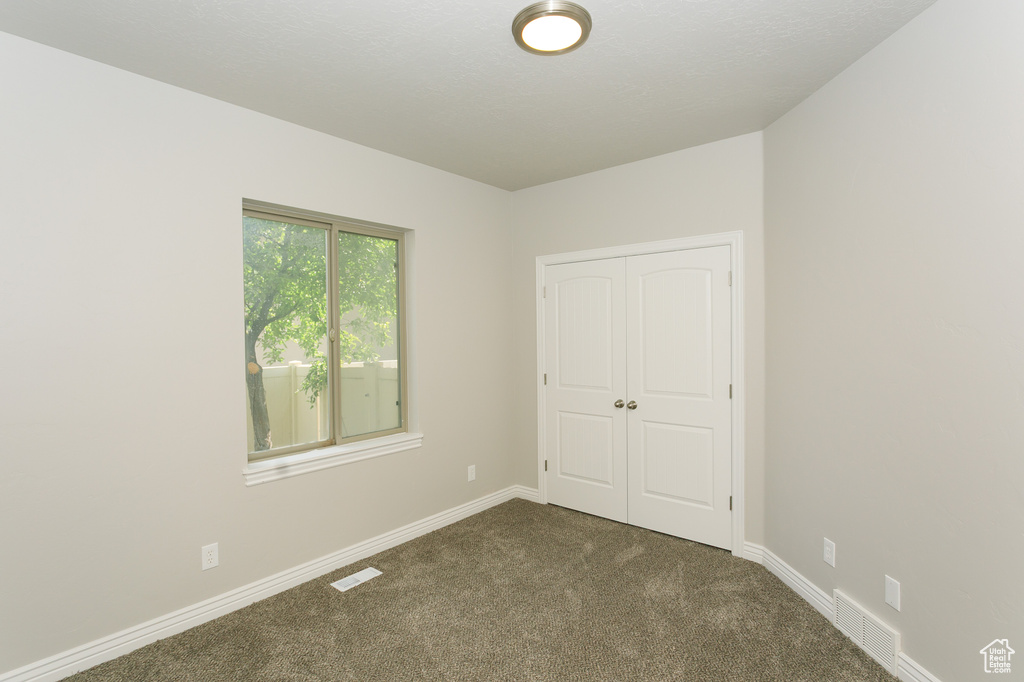 Unfurnished bedroom featuring dark colored carpet and a closet