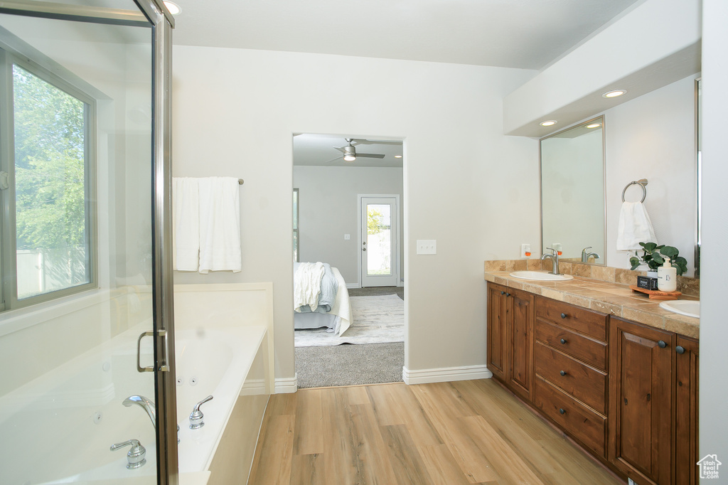 Ensuite bathroom with wood finished floors, double vanity, a garden tub, ceiling fan, and recessed lighting