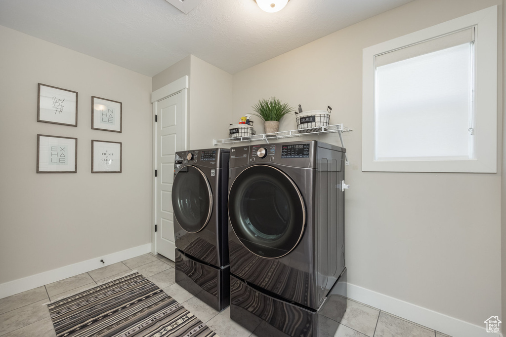 Laundry area with washer and clothes dryer and light tile patterned floors
