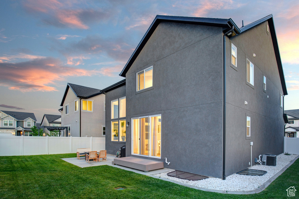 Back of house at dusk with a patio area and stucco siding