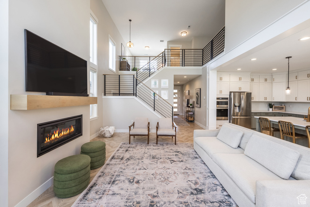 Living area with stairway, a glass covered fireplace, a high ceiling, and recessed lighting