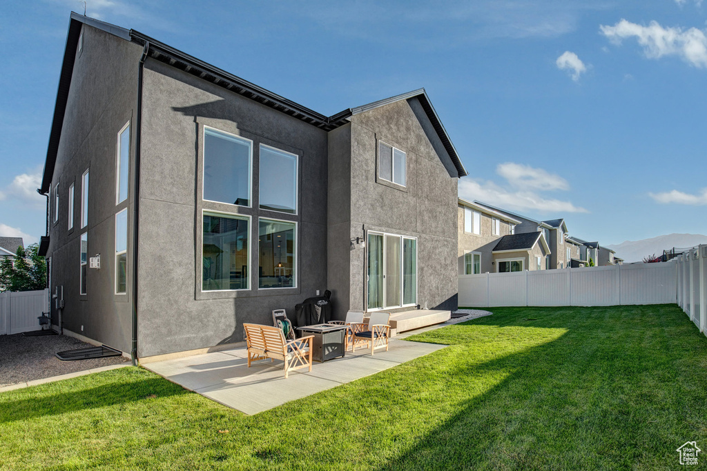 Back of property featuring stucco siding, a patio, a fenced backyard, and an outdoor fire pit