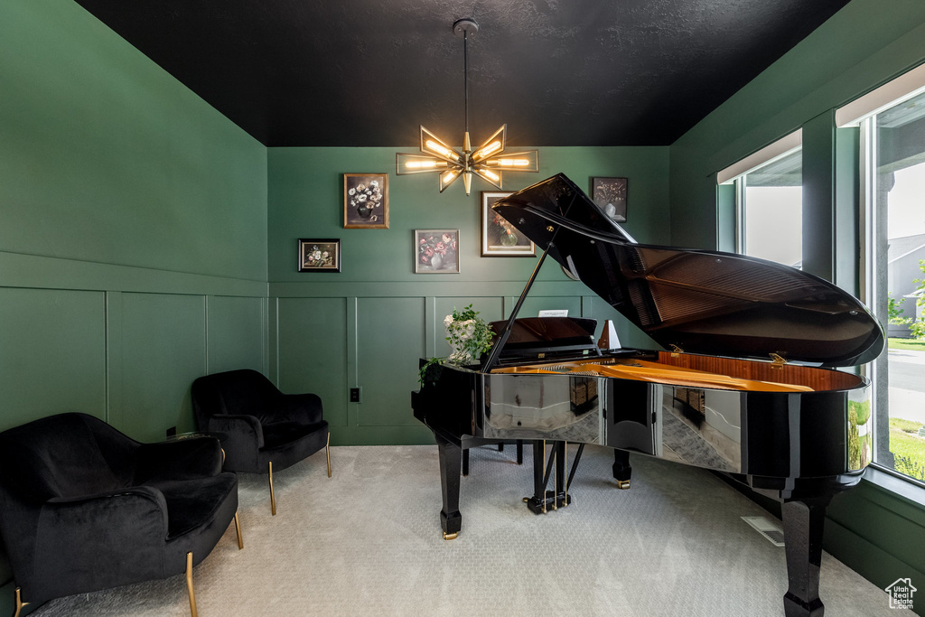Living area featuring a decorative wall, carpet flooring, a chandelier, and a wainscoted wall
