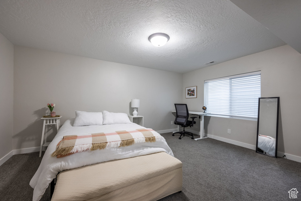 Carpeted bedroom with a textured ceiling and baseboards