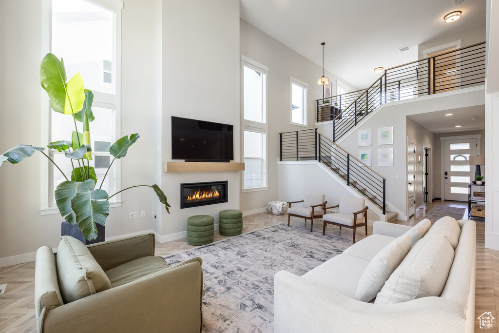 Living room with stairway, a high ceiling, and a glass covered fireplace