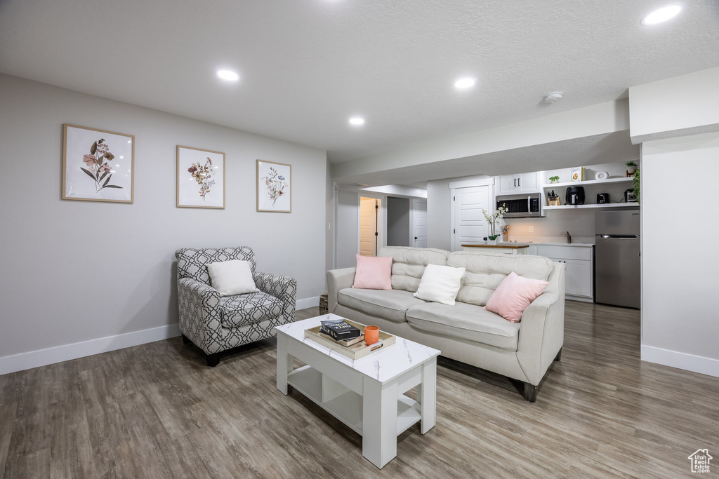 Living area with light wood-style flooring, recessed lighting, and bar area