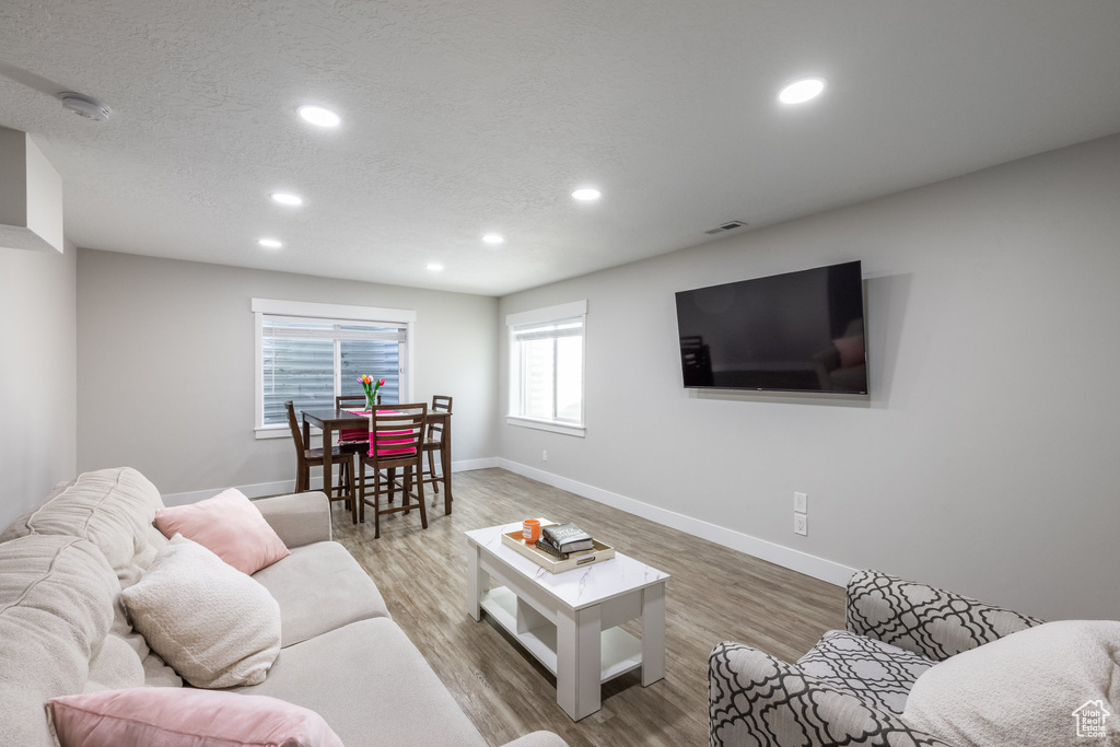 Living area with recessed lighting, wood finished floors, and a textured ceiling