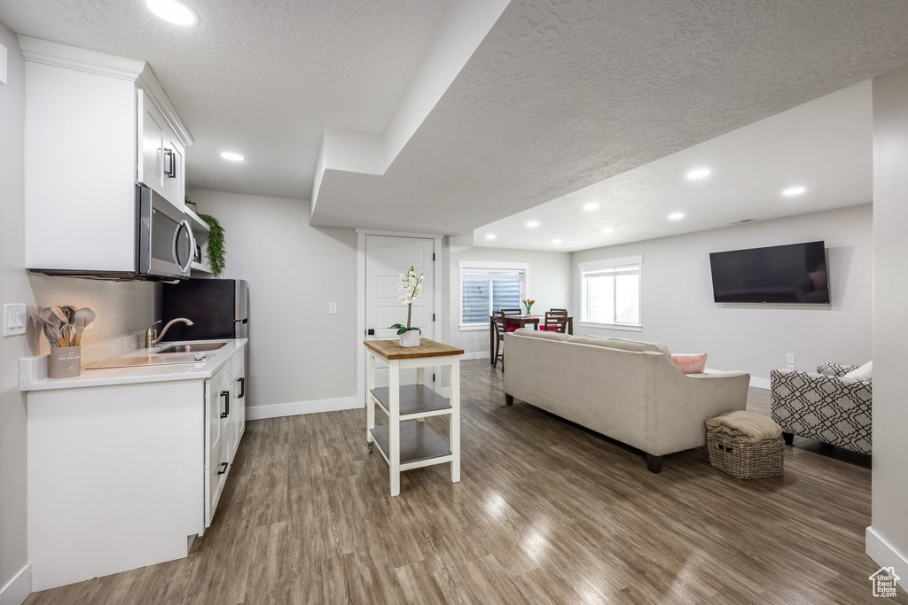 Living area featuring wood finished floors, a textured ceiling, and recessed lighting