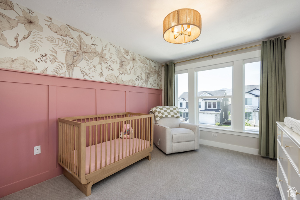 Carpeted bedroom with a nursery area, a decorative wall, a wainscoted wall, and wallpapered walls