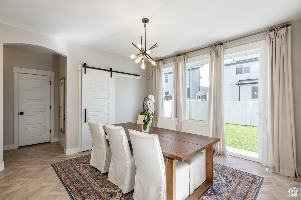 Dining space with a barn door, arched walkways, and a chandelier