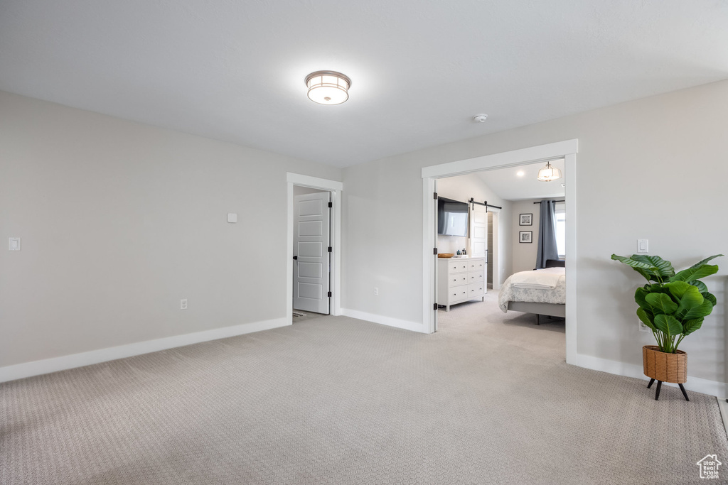 Bedroom featuring light colored carpet and a barn door