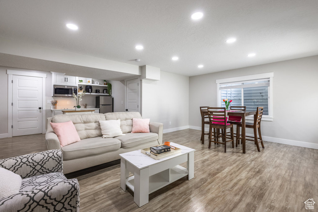 Living area with recessed lighting, wet bar, and wood finished floors