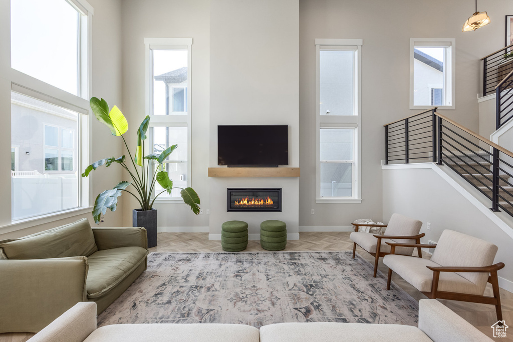 Living area with plenty of natural light, a glass covered fireplace, and stairs
