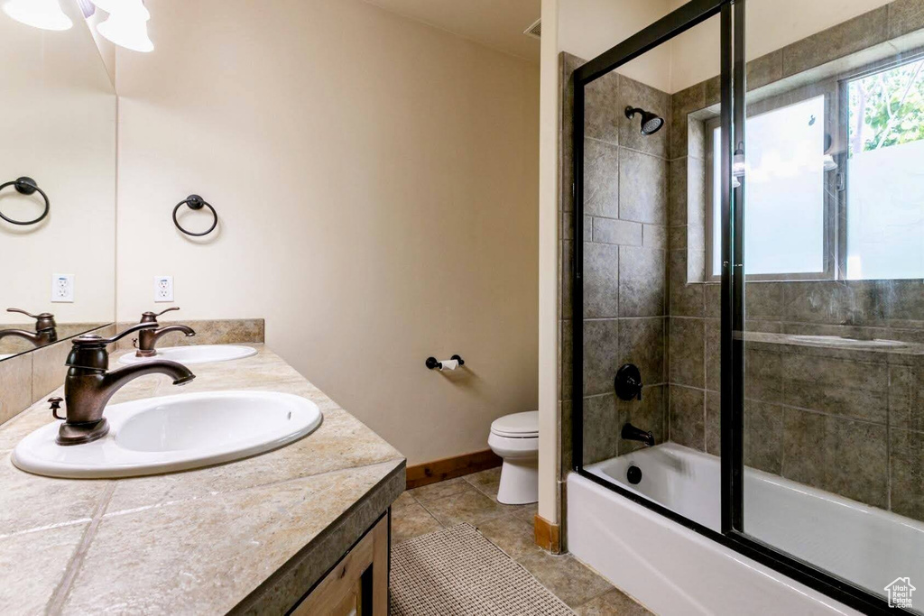 Full bathroom featuring double vanity, combined bath / shower with glass door, and tile patterned flooring