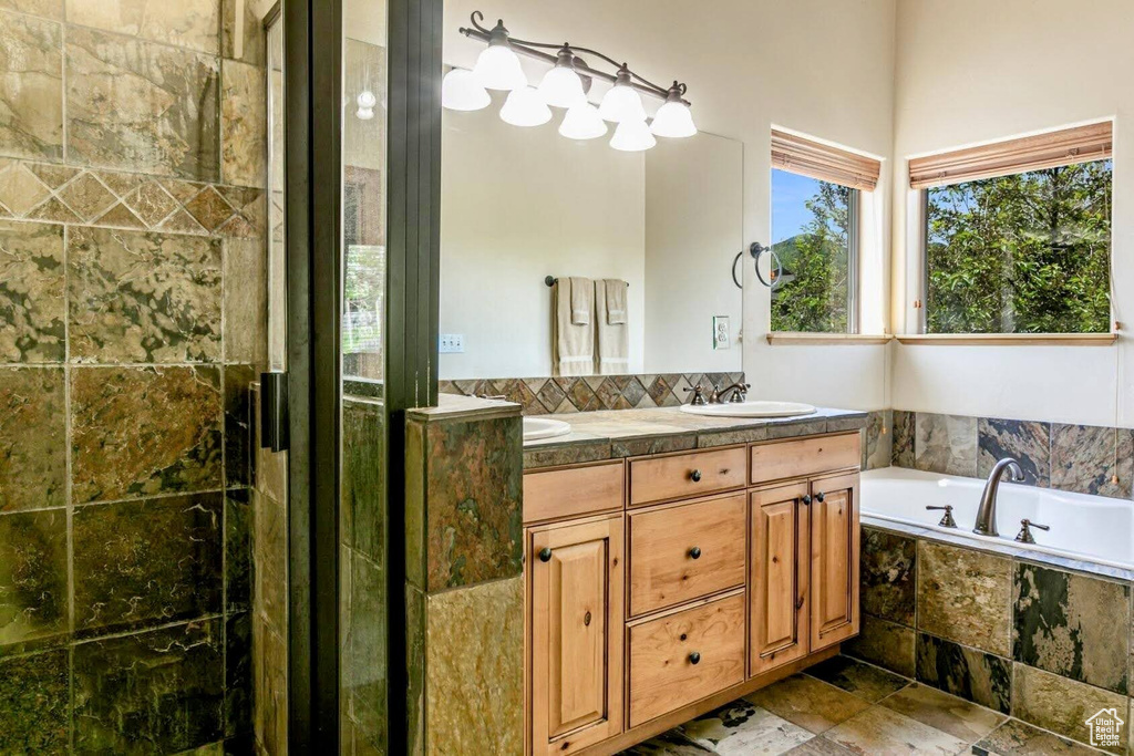 Full bath featuring double vanity, a garden tub, and stone finish floors
