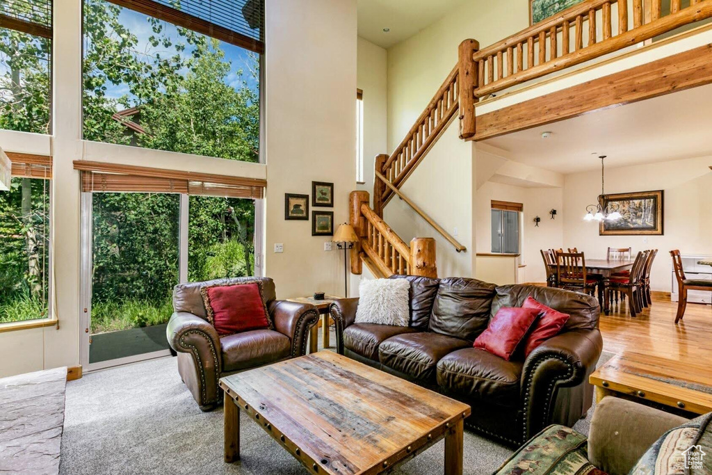 Living room with stairway, a towering ceiling, plenty of natural light, and a chandelier