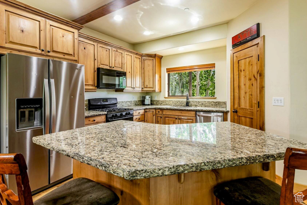 Kitchen featuring stainless steel appliances, a kitchen breakfast bar, light stone counters, a kitchen island, and recessed lighting