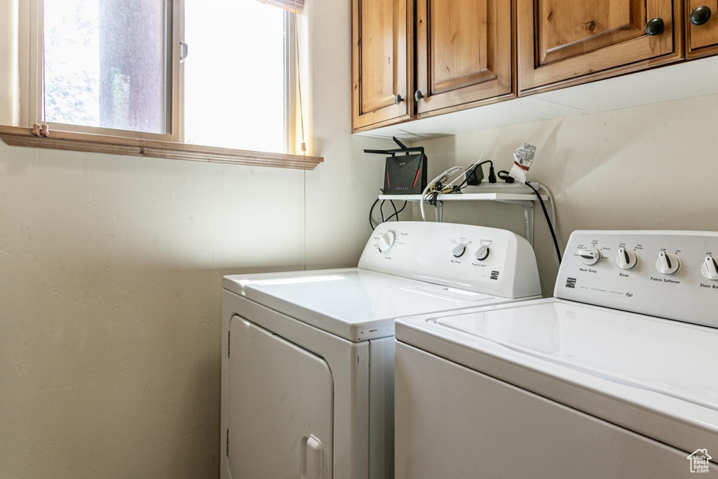 Laundry area with separate washer and dryer, cabinet space, and plenty of natural light