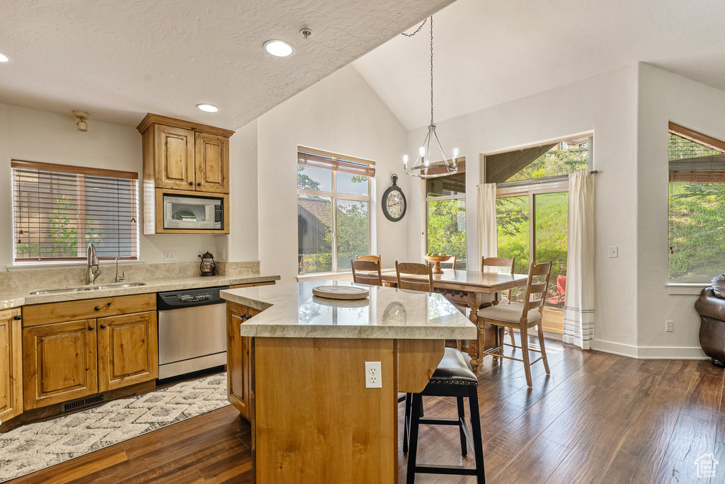 Kitchen with stainless steel appliances, a kitchen island, a kitchen bar, lofted ceiling, and a chandelier
