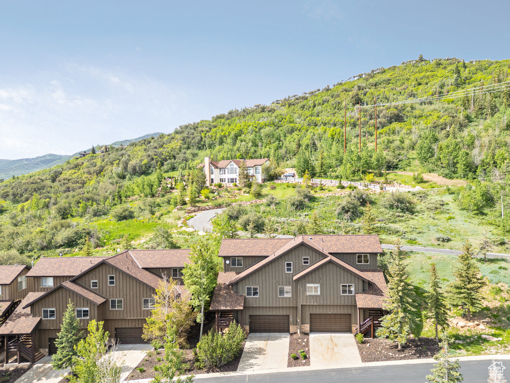 Aerial view of property and surrounding area with a forest and mountains