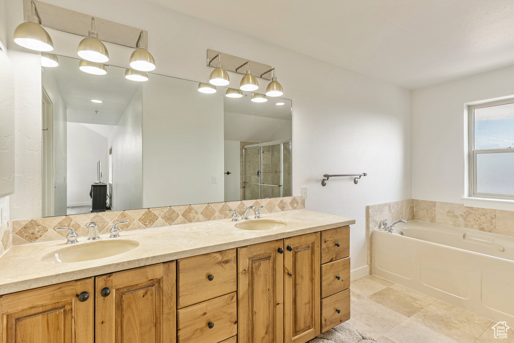 Bathroom with double vanity, a stall shower, a garden tub, and backsplash
