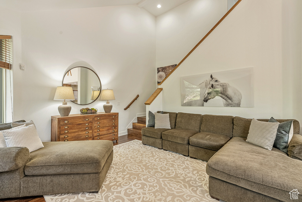 Living room featuring stairs, lofted ceiling, wood finished floors, and recessed lighting