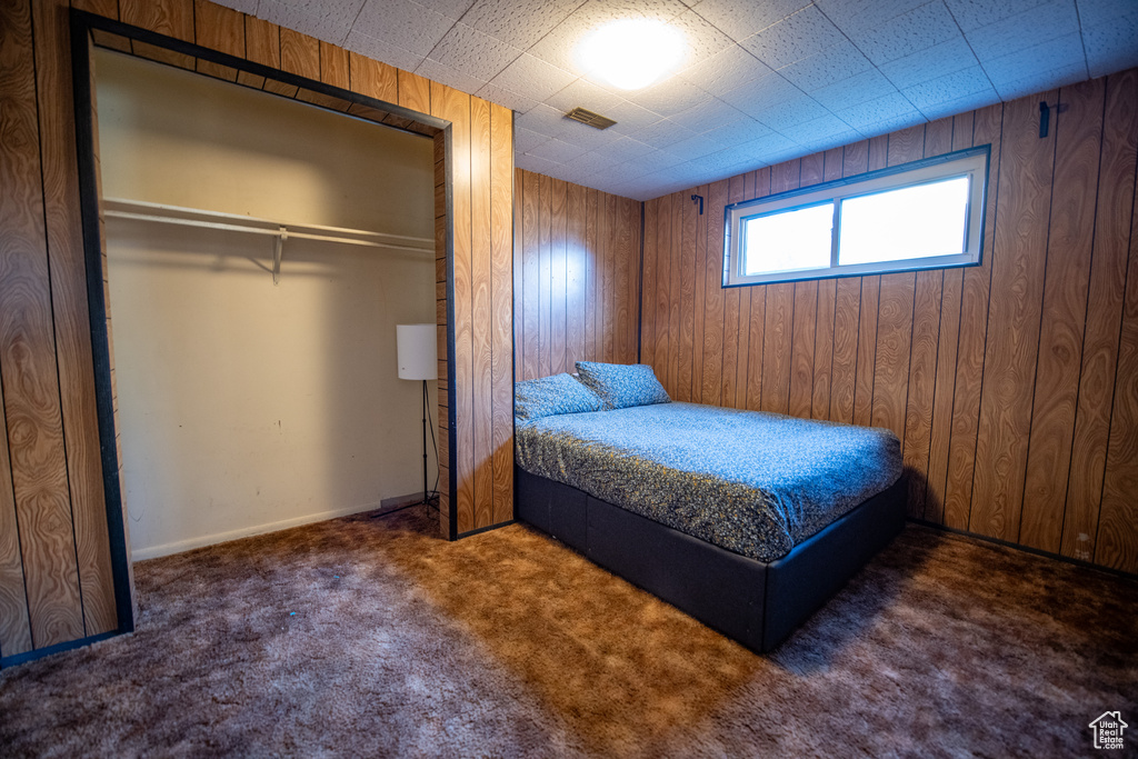 Bedroom featuring carpet, wooden walls, and a closet