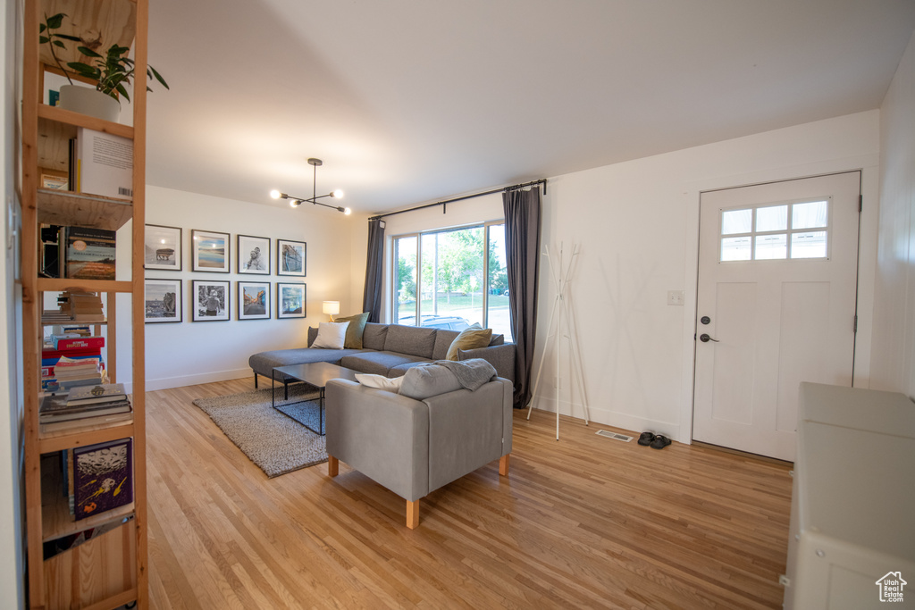 Living room featuring light wood-style flooring, a chandelier, and healthy amount of natural light
