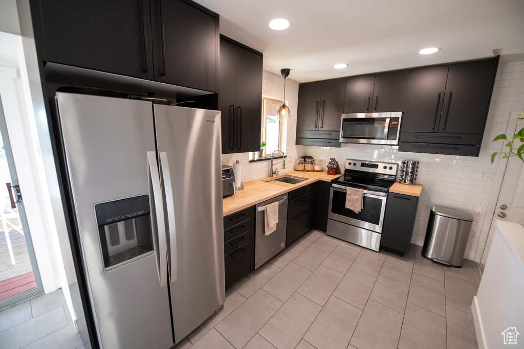 Kitchen featuring stainless steel appliances, decorative backsplash, pendant lighting, butcher block countertops, and recessed lighting