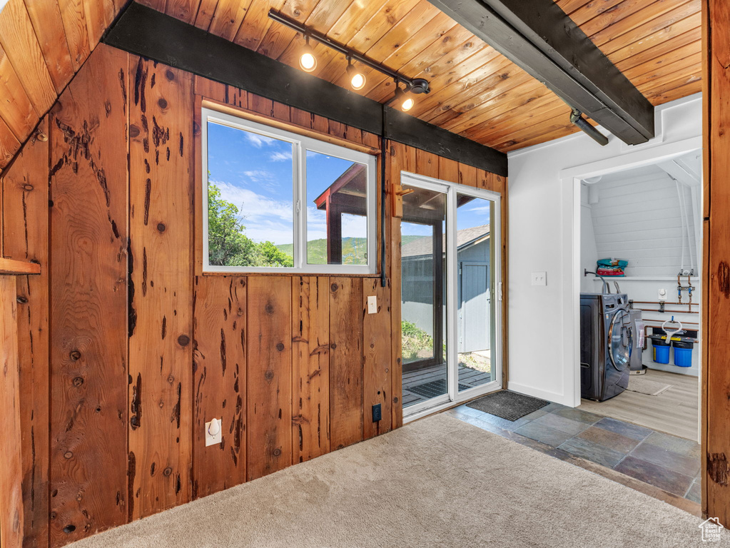 Doorway to outside featuring stone tile flooring, wooden ceiling, track lighting, and wood walls