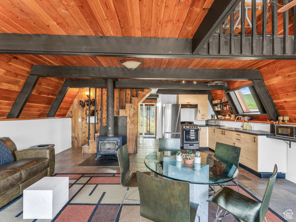 Dining space featuring wooden ceiling, plenty of natural light, and a wood stove