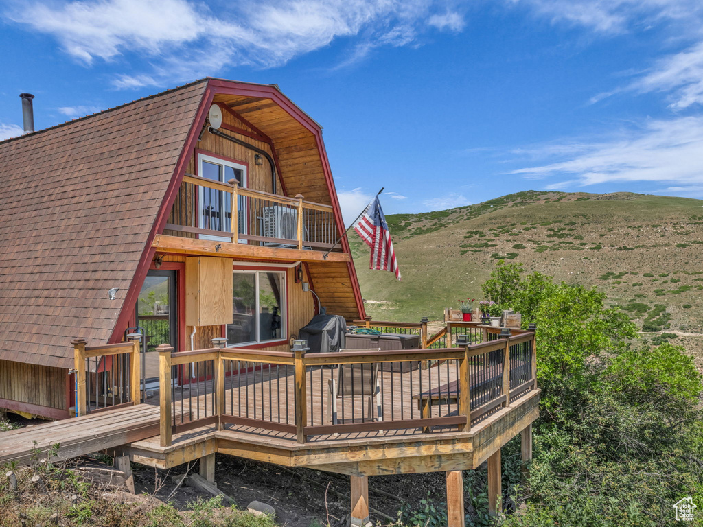 Rear view of house featuring a deck with mountain view, a gambrel roof, and stairway
