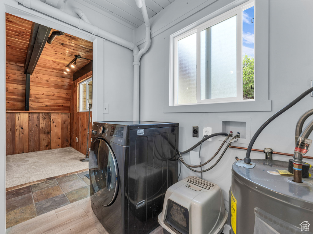 Washroom featuring washer / dryer, wooden ceiling, wooden walls, water heater, and stone finish floors