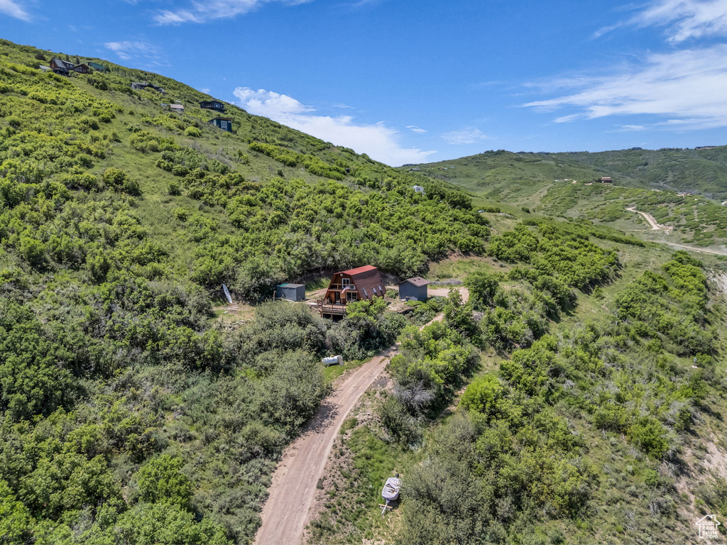 View from above of property featuring a mountainous background and a heavily wooded area