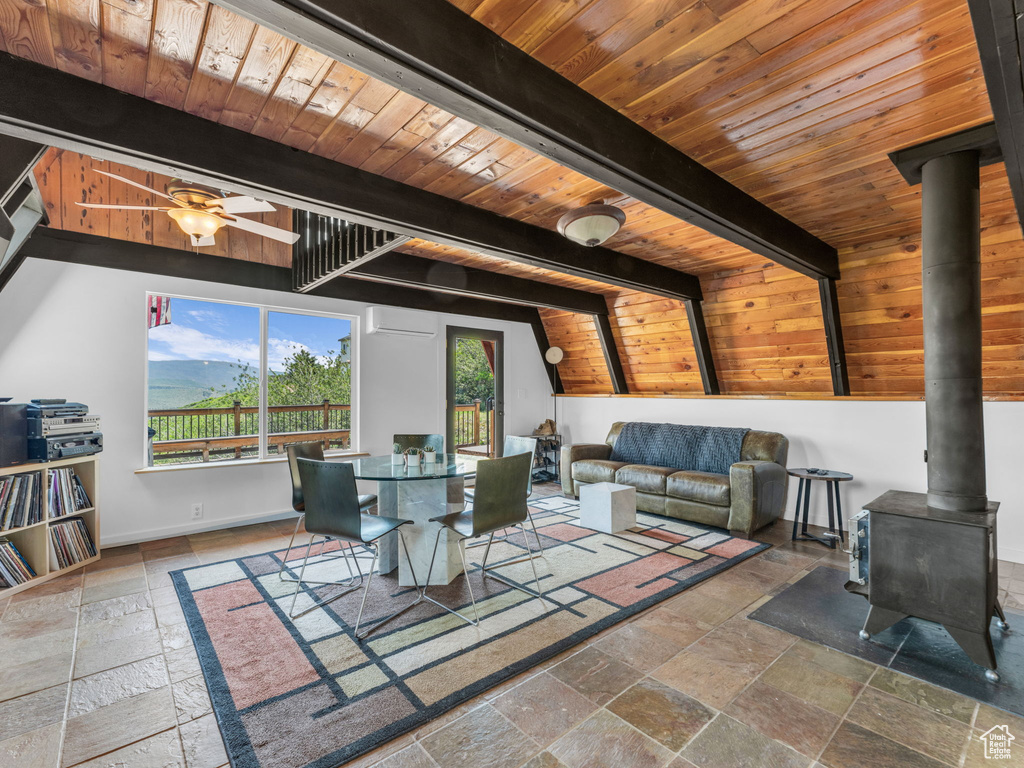 Dining room with stone tile floors, a wood stove, wood ceiling, a wall mounted air conditioner, and ceiling fan