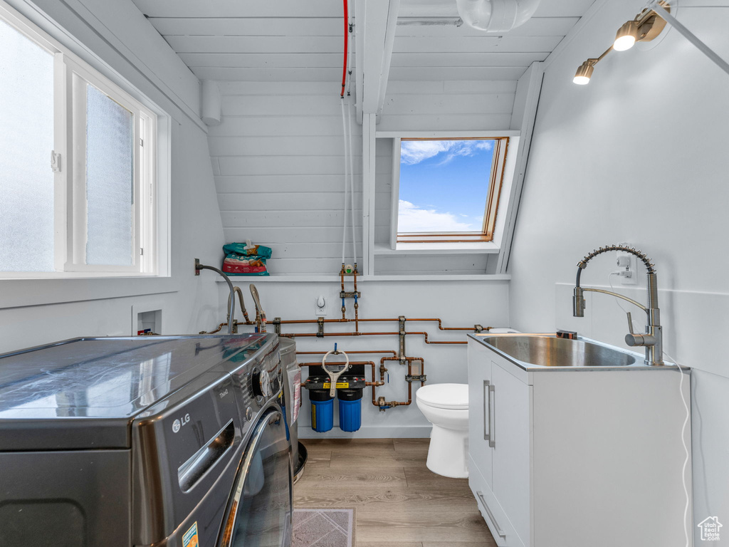 Laundry room with washer / clothes dryer, light wood finished floors, and healthy amount of natural light
