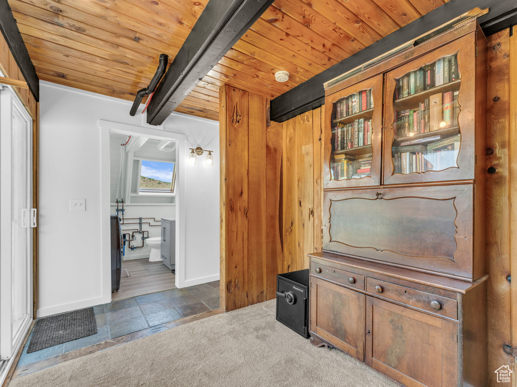 Interior space featuring a wood ceiling with exposed beams and stone finish floors