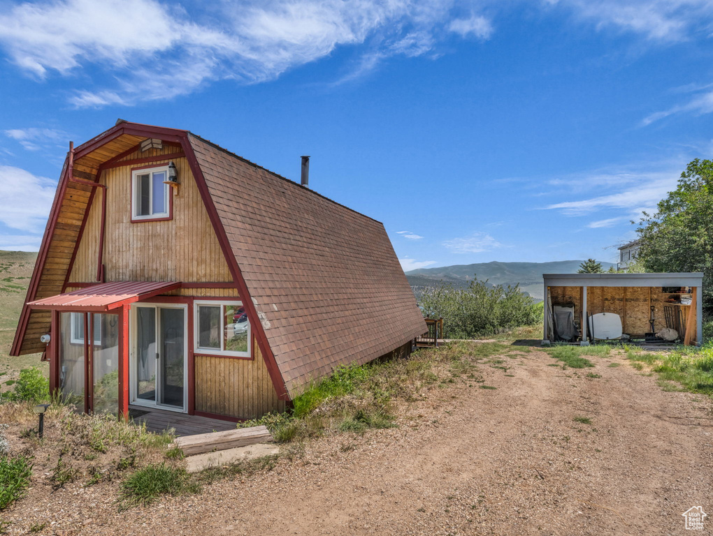 View of side of home featuring a mountain view and a gambrel roof