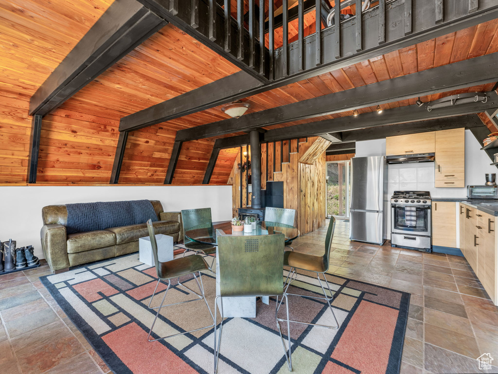 Living room with a wood stove, stone finish flooring, and a wood ceiling with exposed beams